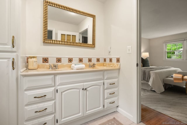 ensuite bathroom featuring double vanity and baseboards
