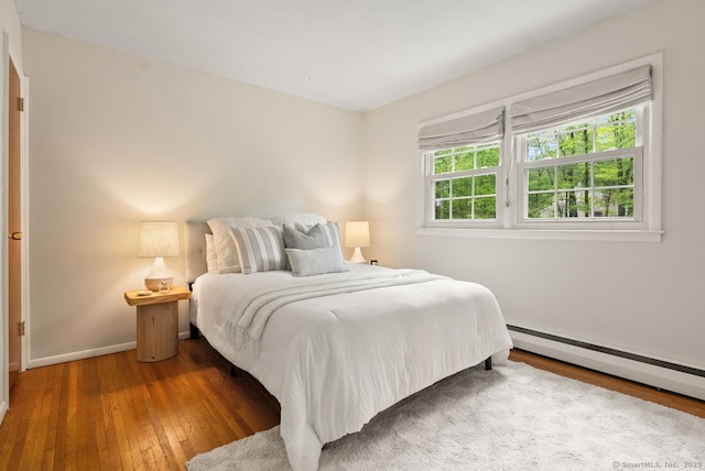 bedroom featuring hardwood / wood-style flooring, baseboards, and baseboard heating