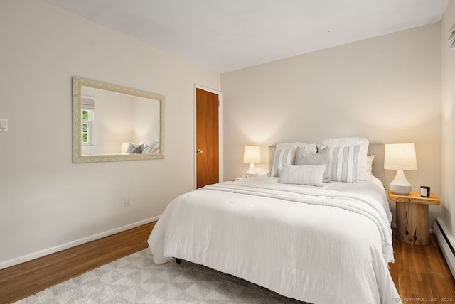 bedroom featuring a baseboard radiator, wood finished floors, and baseboards