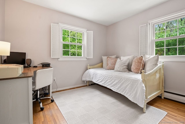bedroom featuring wood finished floors, an office area, and baseboards