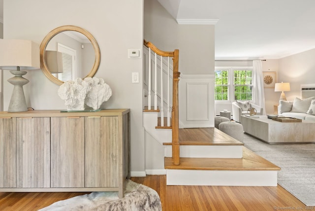 stairway featuring crown molding, wood finished floors, and baseboards