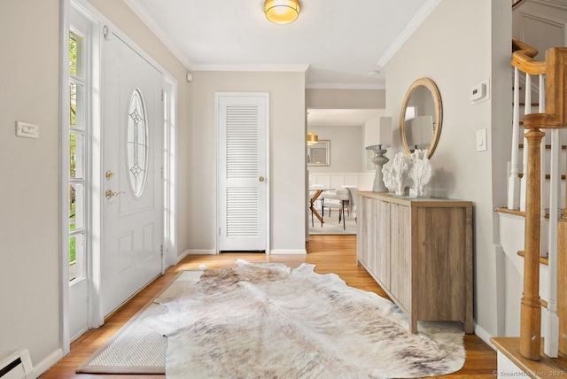 foyer entrance featuring crown molding, a baseboard radiator, and light wood-style floors
