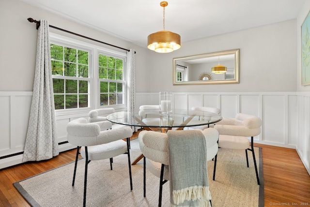 dining room with a wainscoted wall, a decorative wall, and wood finished floors