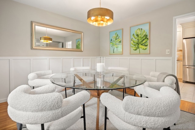 dining room with a decorative wall, a wainscoted wall, and wood finished floors