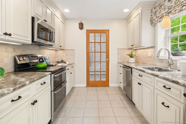 kitchen with stainless steel appliances, a sink, light stone counters, decorative backsplash, and light tile patterned floors