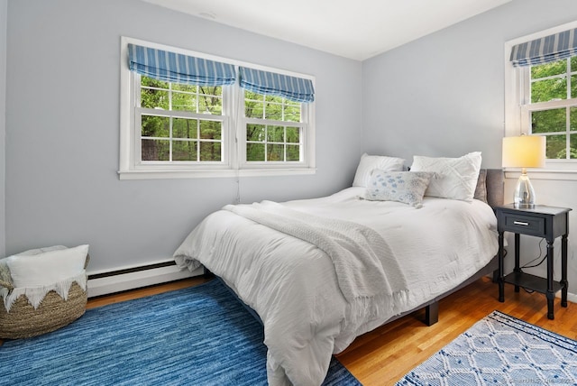bedroom with baseboard heating and wood finished floors