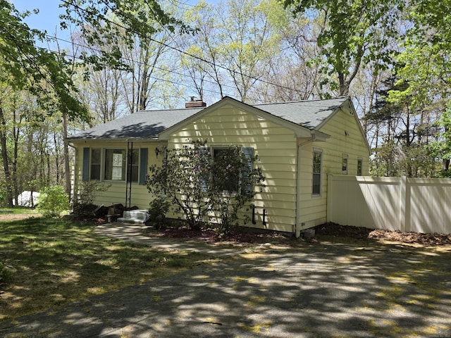 view of front of property featuring fence, a shingled roof, and a chimney