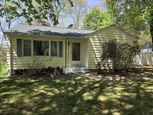 view of front facade with roof with shingles and a front lawn