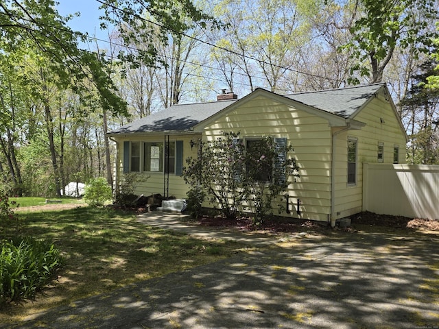 view of front of property with a shingled roof, fence, and a chimney