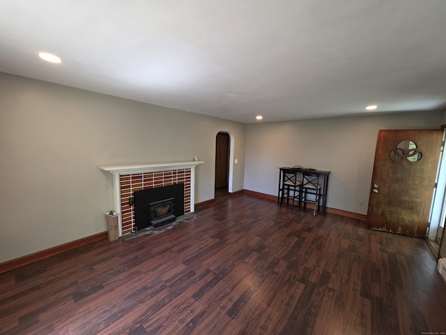 unfurnished living room featuring arched walkways, recessed lighting, a tiled fireplace, and wood finished floors