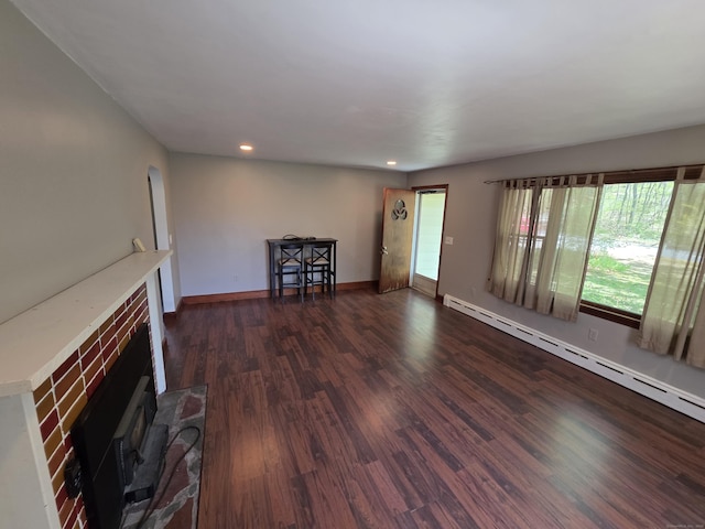 unfurnished living room featuring baseboards, dark wood-type flooring, recessed lighting, a baseboard heating unit, and arched walkways