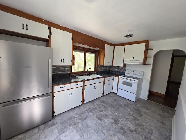 kitchen featuring white range with electric stovetop, a sink, arched walkways, freestanding refrigerator, and under cabinet range hood