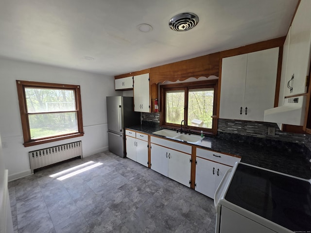 kitchen featuring a sink, range, radiator, freestanding refrigerator, and under cabinet range hood