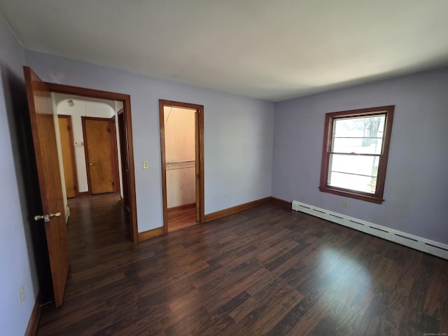 unfurnished room featuring baseboards, a baseboard heating unit, and dark wood-type flooring