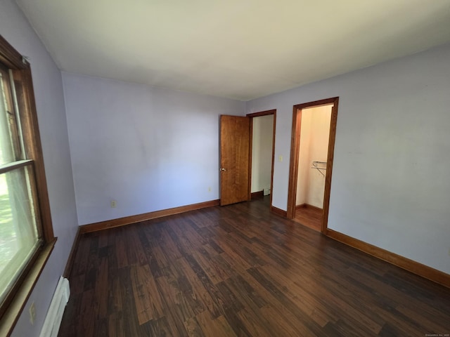 unfurnished bedroom with dark wood-style flooring, baseboards, and baseboard heating