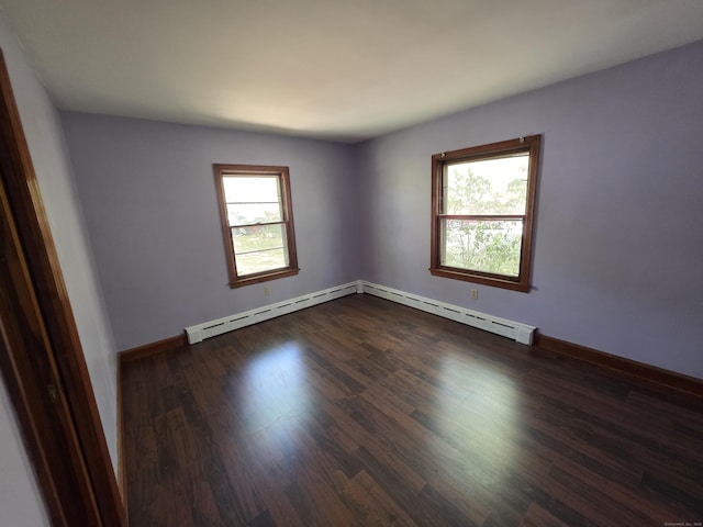 empty room featuring baseboards, baseboard heating, a baseboard heating unit, and dark wood-style floors