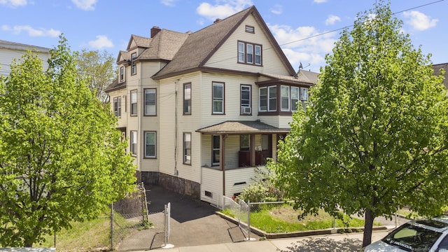 victorian house featuring fence and a shingled roof