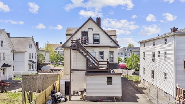 back of house featuring stairway, fence, a residential view, and a chimney