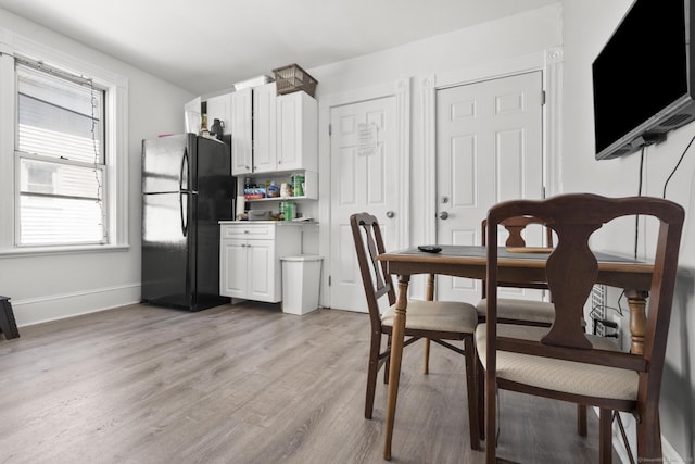 dining area featuring light wood-type flooring and baseboards