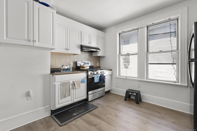 kitchen with baseboards, under cabinet range hood, white cabinets, and stainless steel gas range