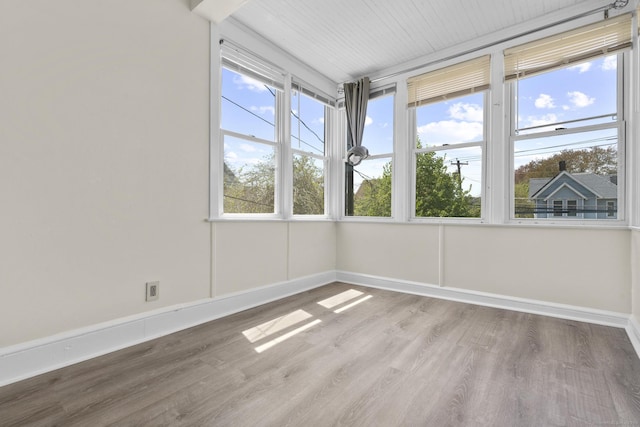 unfurnished sunroom featuring baseboards and wood finished floors