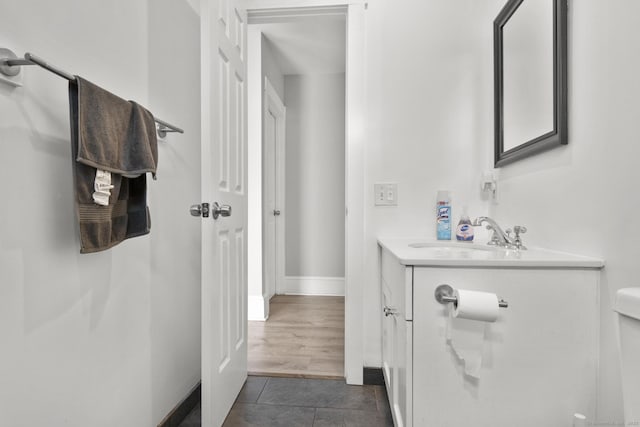 bathroom featuring toilet, tile patterned floors, baseboards, and vanity