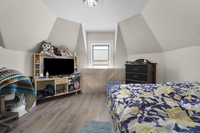 bedroom with wood finished floors and lofted ceiling