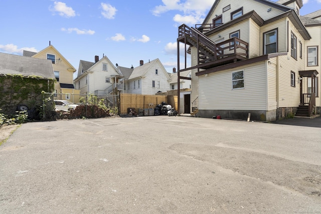 view of side of property featuring fence, a balcony, and a residential view