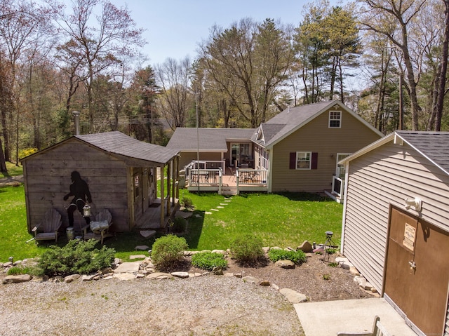 rear view of property with a shingled roof, a storage shed, a deck, an outbuilding, and a yard