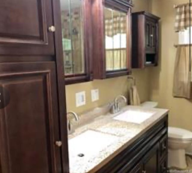 bathroom with double vanity, a sink, and toilet