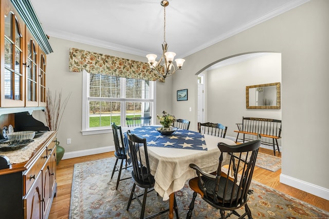 dining area with crown molding, arched walkways, baseboards, and a notable chandelier