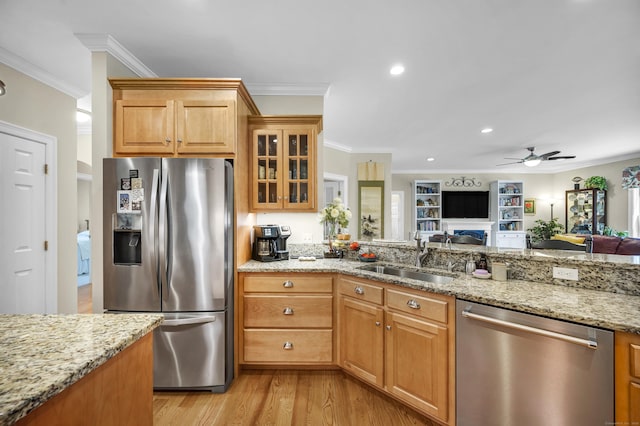 kitchen featuring crown molding, light stone countertops, appliances with stainless steel finishes, a sink, and light wood-style floors