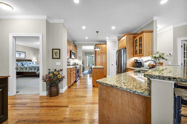 kitchen featuring light stone countertops, light wood-type flooring, a center island, a sink, and appliances with stainless steel finishes