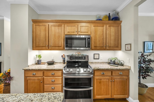 kitchen featuring appliances with stainless steel finishes, light stone counters, brown cabinetry, wood finished floors, and ornamental molding