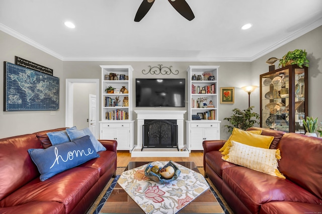 living area featuring crown molding, a fireplace with raised hearth, a ceiling fan, and recessed lighting