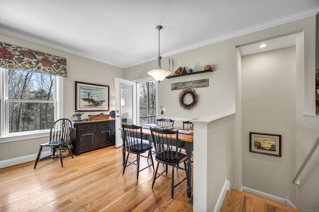 dining space featuring light wood-style floors, baseboards, and crown molding
