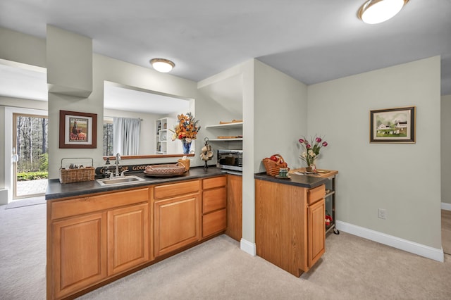kitchen featuring a sink, dark countertops, stainless steel microwave, and light carpet