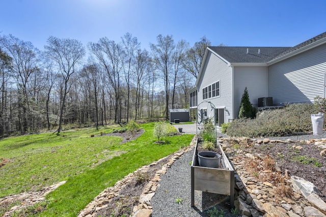 view of yard with central AC unit and a garden