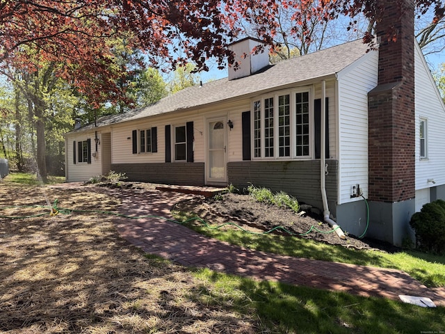 single story home featuring brick siding, roof with shingles, and a chimney