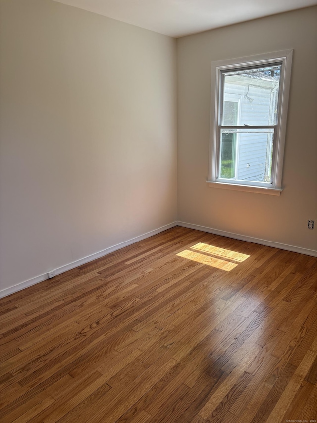 unfurnished room with baseboards and wood finished floors
