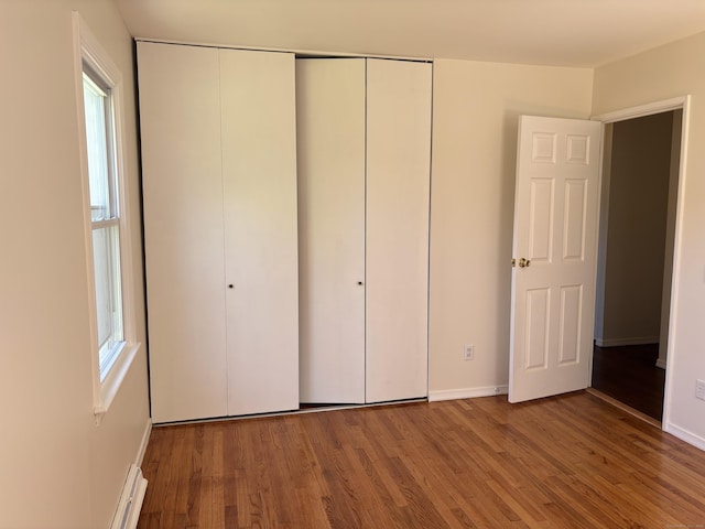 unfurnished bedroom featuring multiple windows, a closet, and wood finished floors
