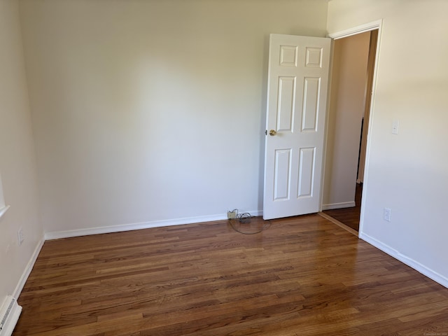 unfurnished room with baseboards, baseboard heating, and dark wood-style flooring