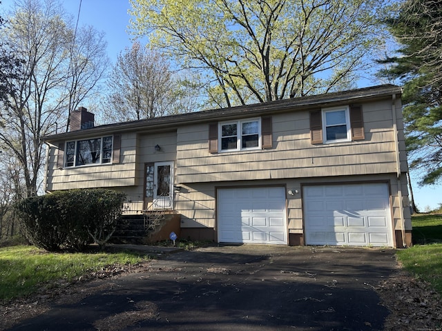 split foyer home featuring driveway, a chimney, and a garage