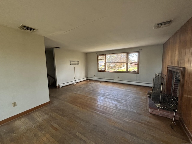 unfurnished living room with wood walls, visible vents, dark wood finished floors, and a fireplace