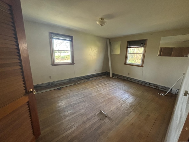unfurnished bedroom with a baseboard heating unit, hardwood / wood-style floors, and multiple windows