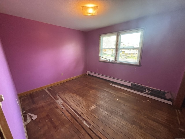 empty room featuring baseboards, baseboard heating, and hardwood / wood-style floors
