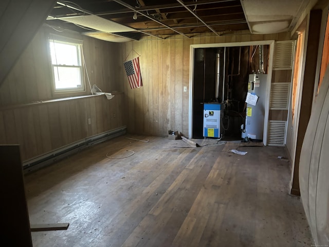below grade area with a baseboard radiator, gas water heater, and hardwood / wood-style floors