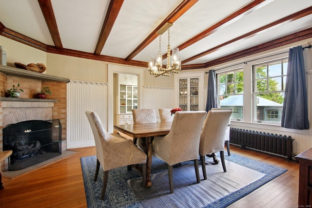 836 Prospect Ave, Hartford, CT 06105 - dining room with radiator heating unit, light wood-style flooring, a chandelier, beamed ceiling, and a wainscoted wall
