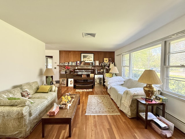 living area featuring visible vents, a baseboard radiator, a wealth of natural light, and wood finished floors