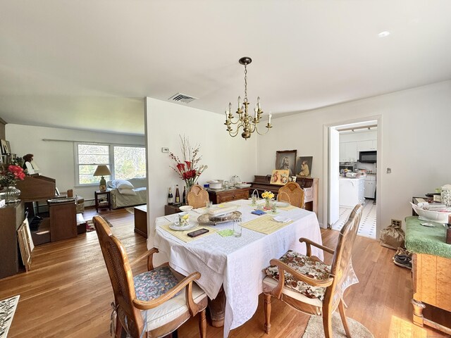 dining area with light wood-style floors, a chandelier, and visible vents